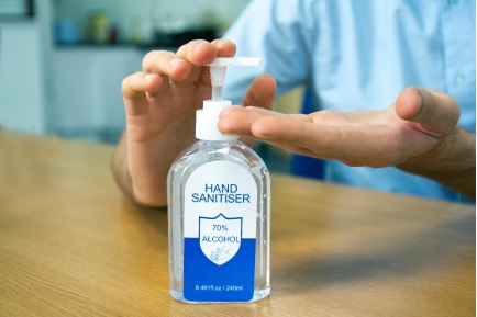 person squeezing out sanitizer from a bottle